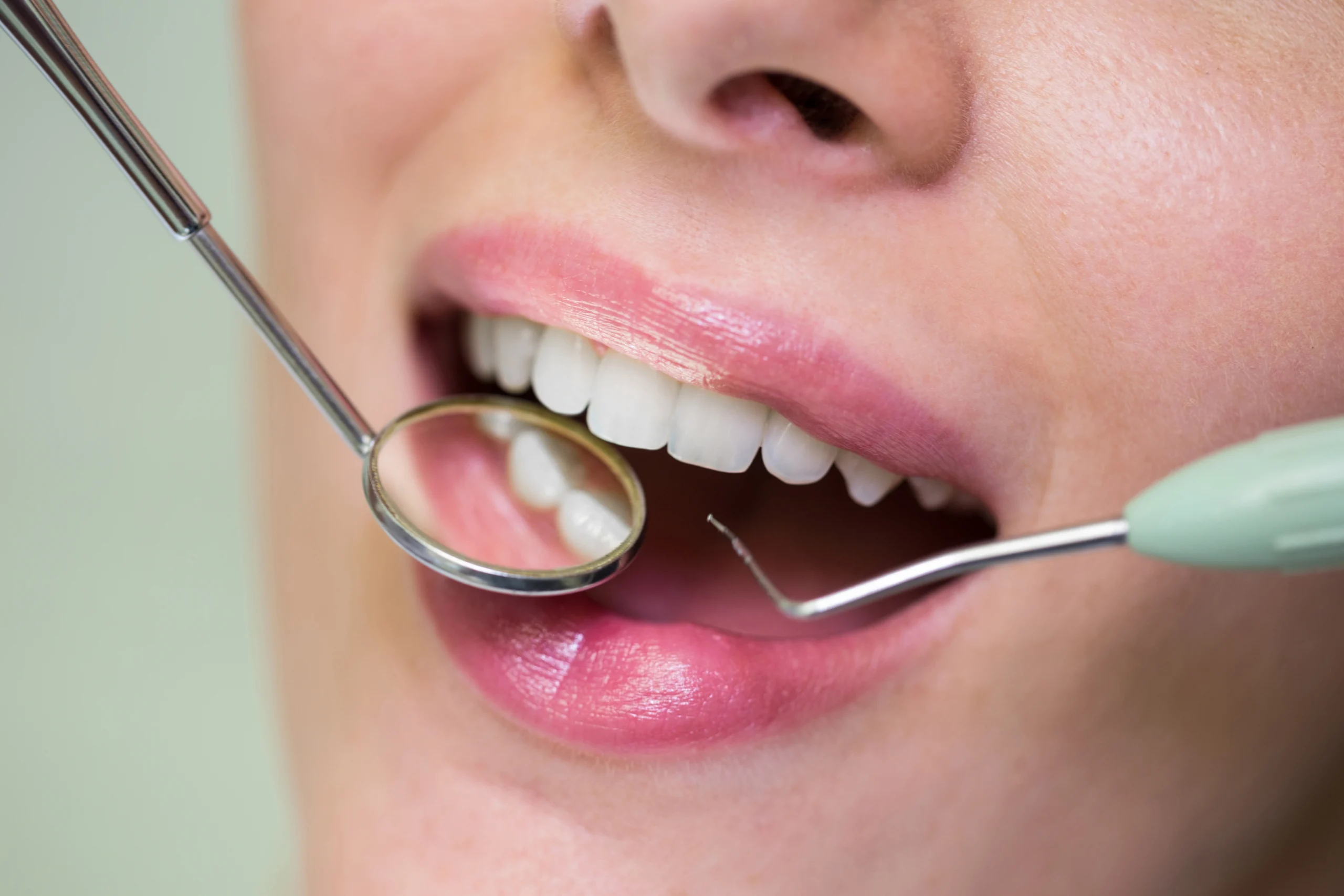 dentist examining female patient with tools